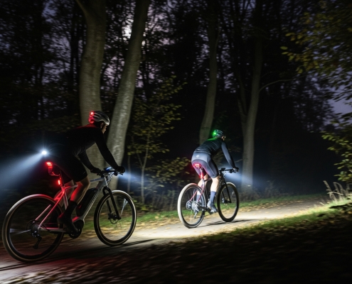Zwei Radfahrr fahren durch den nächtlichen Wald mit LED Lichtern