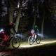 Zwei Radfahrr fahren durch den nächtlichen Wald mit LED Lichtern